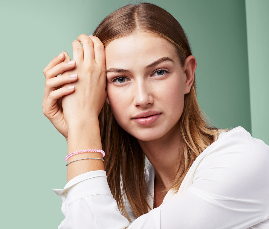Porträt einer Frau, die ein Armband mit facettierten Glassteinen trägt.