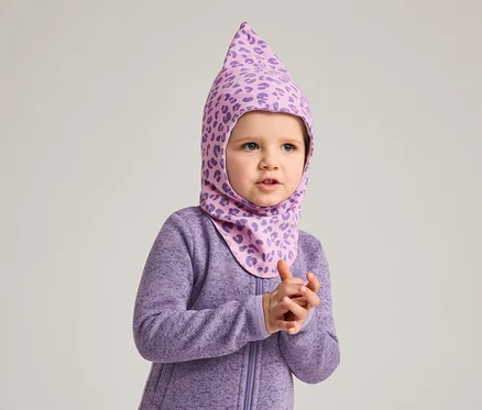 Ein kleines Kind trägt einen lila Overall und eine lila Sturmhaube mit Leopardenmuster.
