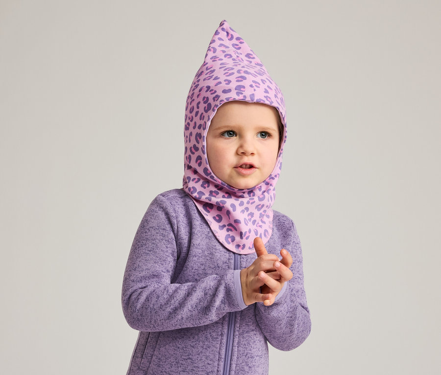 Ein kleines Kind trägt einen lila Overall und eine lila Sturmhaube mit Leopardenmuster.