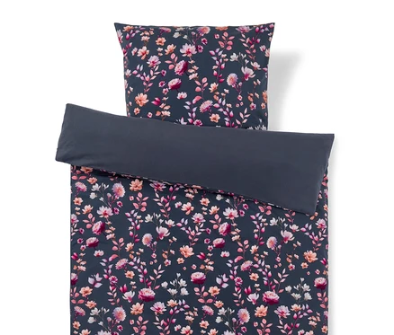 Bettwäsche-Set mit dunkelblau/grauem Blumenmuster in Rosa, Pfirsich und Weiß. Der Bettbezug ist umgeschlagen und zeigt eine einfarbige dunkelblau/graue Unterseite, der Kissenbezug liegt oben.