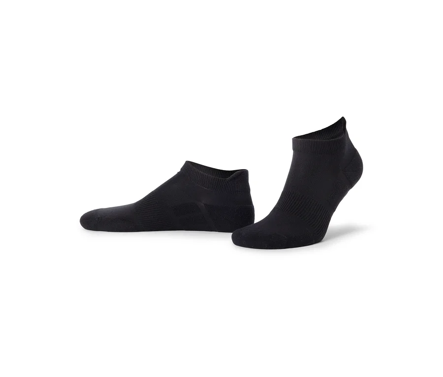 Zwei schwarze Knöchelsocken, eine flach liegend und die andere aufrecht stehend, auf weißem Hintergrund.