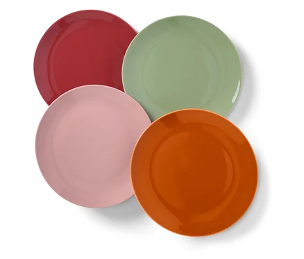 Vier bunte Teller, rot, grün, rosa und orange, überlappen sich leicht auf weißem Hintergrund.