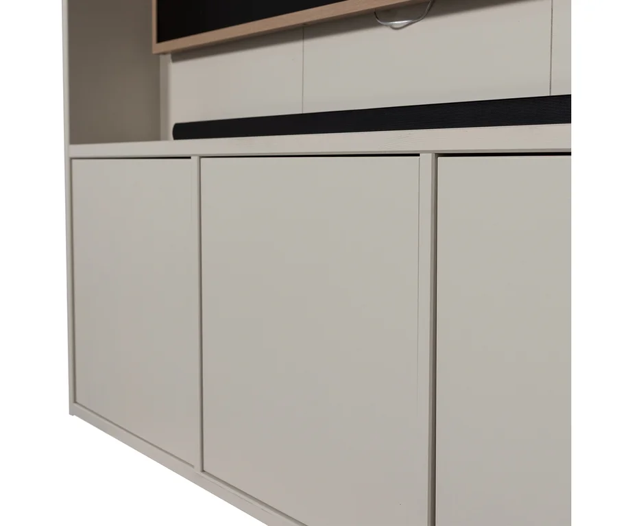 Hellgrauer Schrank mit drei Türen, einer schwarzen Soundbar auf seiner hellen Holzplatte und einem teilweise sichtbaren Fernsehbildschirm darüber.
