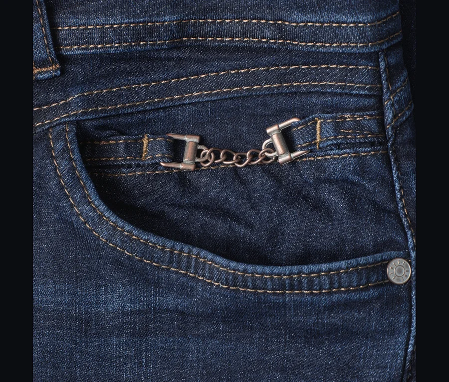Street One Jeans, blau. Nahaufnahme einer Vordertasche mit braunen Nähten, einer dekorativen Metallkette und einem silbernen Niet.