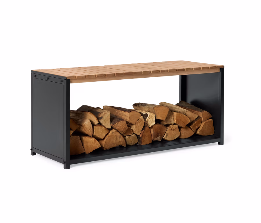 Holzscheite liegen unter einer Bank mit einer Sitzfläche aus Holzlatten und einem anthrazitfarbenen Gestell.