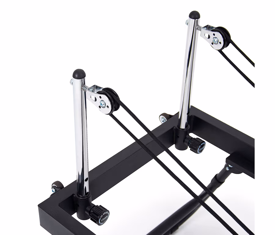 Nahaufnahme des Christopeit Pilates Reformer 2000 mit zwei verchromten Stangen, Rollen und schwarzen Seilen auf einem schwarzen Rahmen.