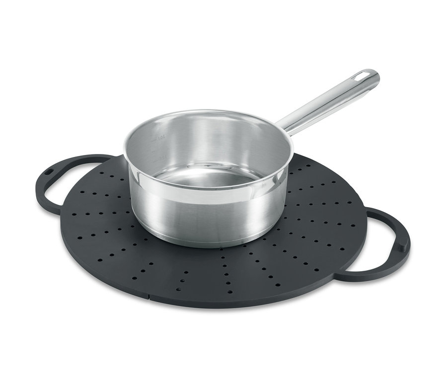 Ein Edelstahltopf steht auf einem schwarzen Küchen-Allrounder mit Löchern und Griffen.