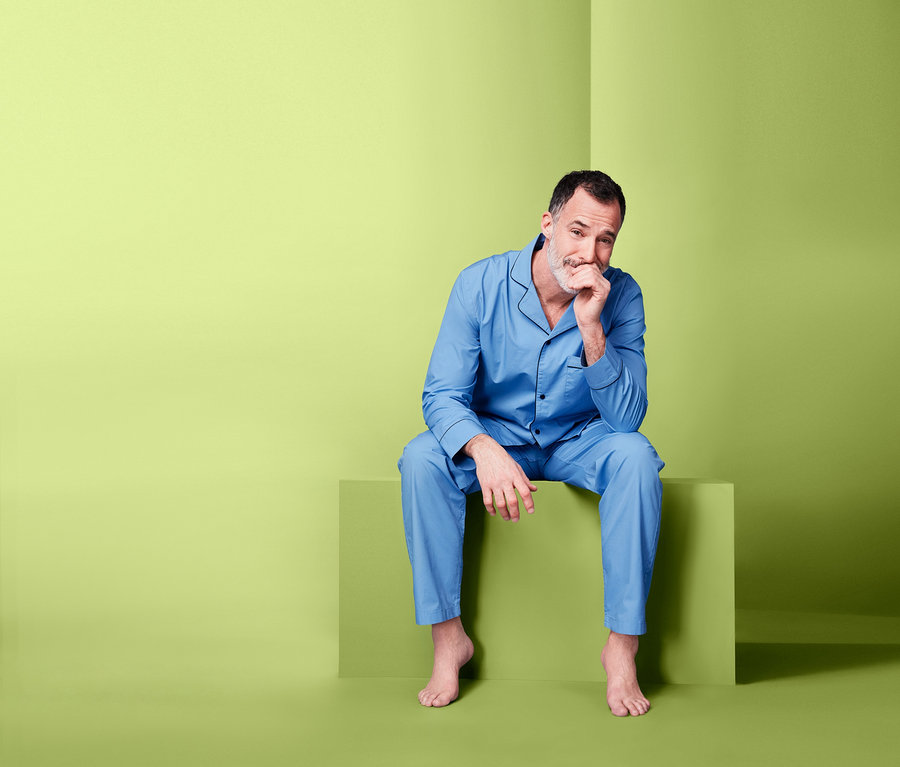 Mann sitzt auf einem grünen Block und trägt einen blauen Web-Pyjama.