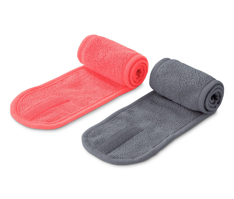 Zwei Kosmetik-Stirnbänder, eins koralle und eins grau, liegen nebeneinander auf einem weißen Hintergrund.