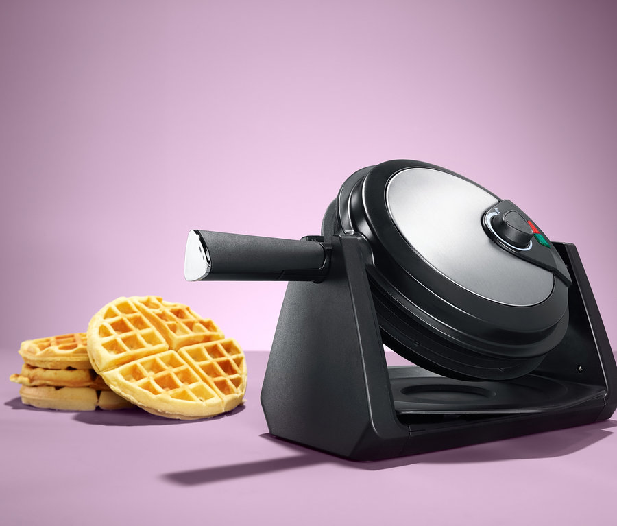 Waffeleisen mit Drehmechanismus neben einem Stapel Waffeln.