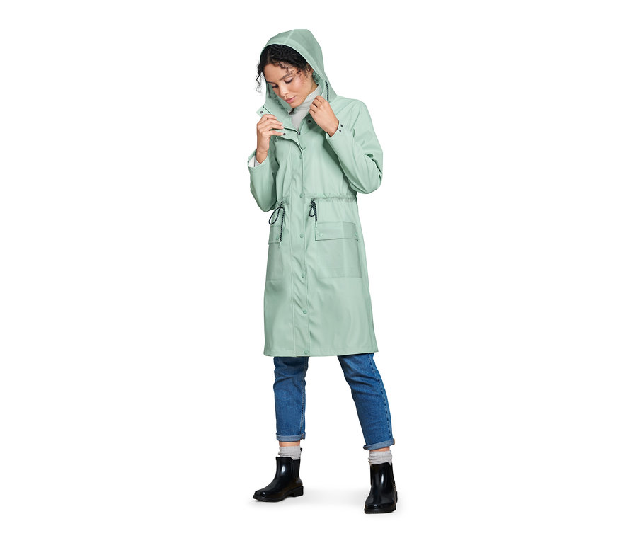Frau justiert die Kapuze einer Regenparka.