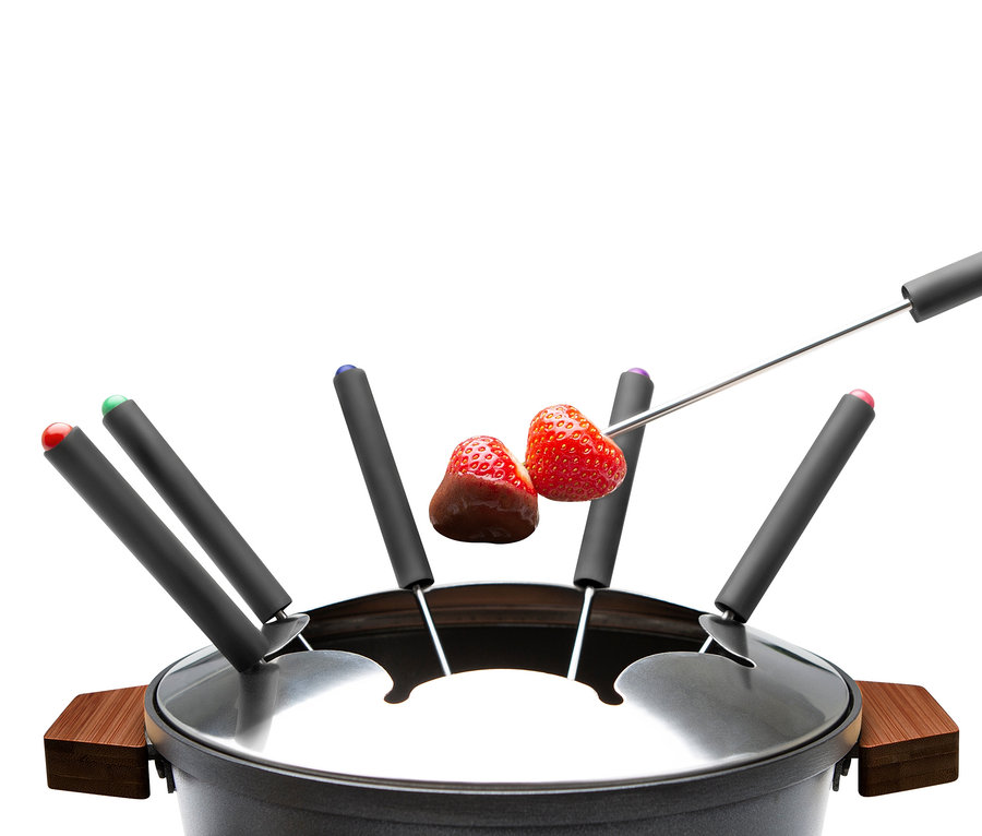 Zwei Erdbeeren auf Gabeln über einem Fondue.