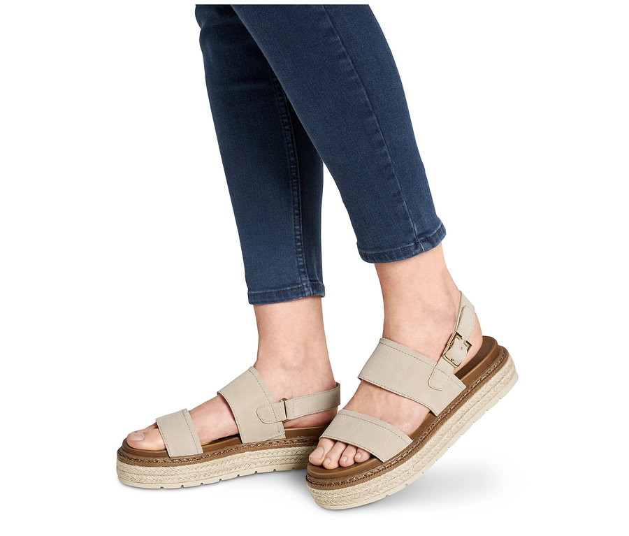 Füße in Jeans tragen Plateau-Sandale aus Leder.