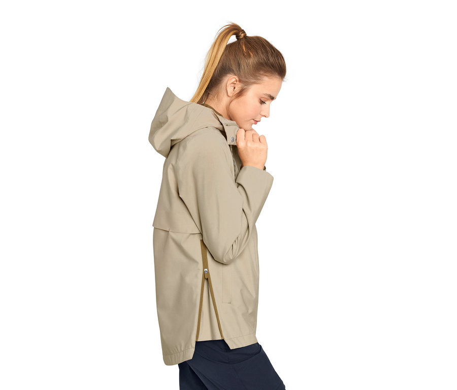 Frau schliesst beige Regenjacke.