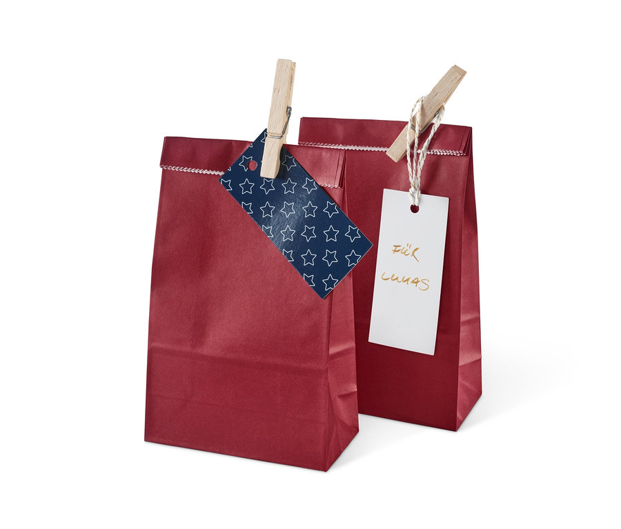 Zwei rote Geschenktüten aus dem Adventskalender-und-Geschenktüten-Set sind mit Wäscheklammern an Karten befestigt.