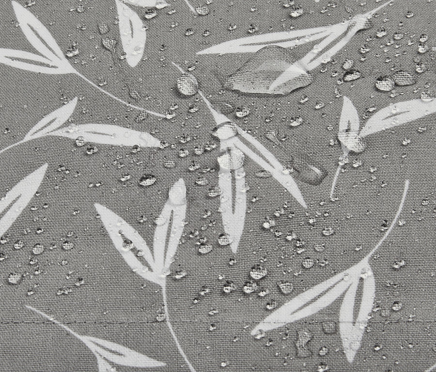 Detailansicht einer grauen Outdoor-Tischdecke mit weißem Blattmuster und Wassertropfen.