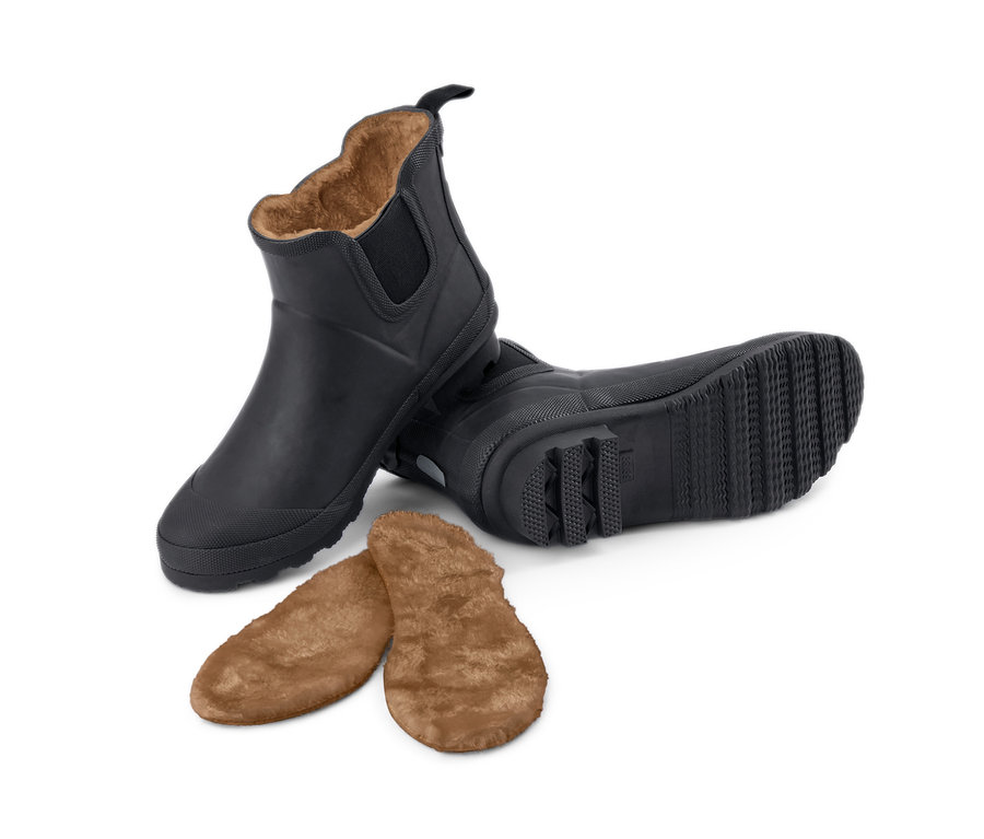Zwei gefütterte, schwarze Regenstiefeletten und Einlegesohlen auf weißem Grund.