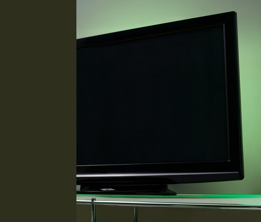 Schwarzer Fernseher mit LED-TV-Hintergrundbeleuchtung auf einem Glastisch.