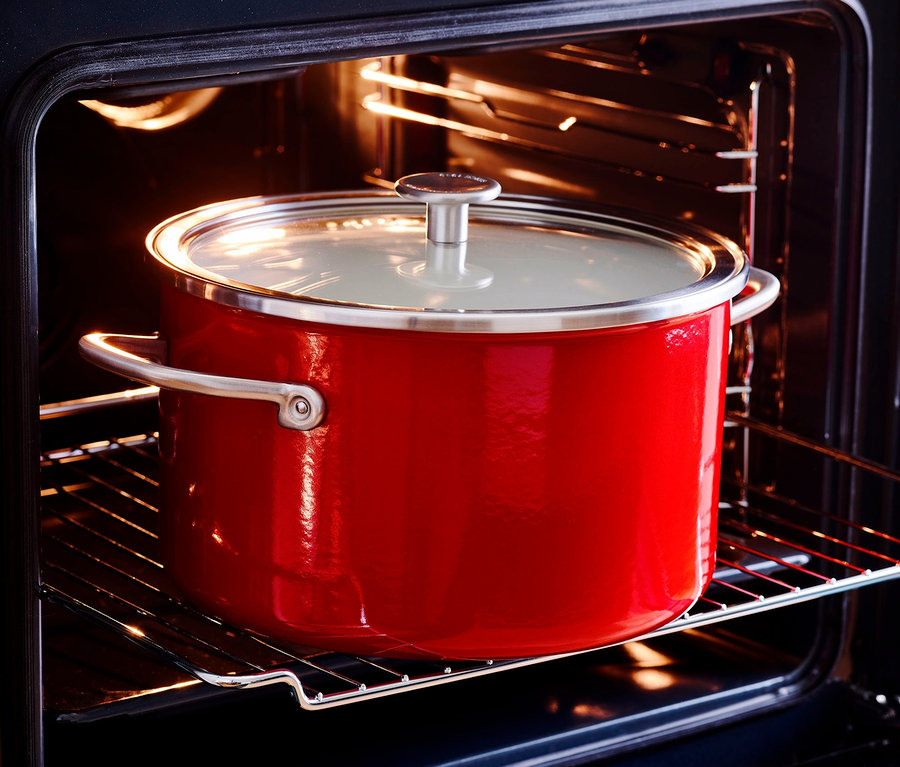 Roter KitchenAid Steel Core Emaille Kochtopf mit Deckel im Ofen.