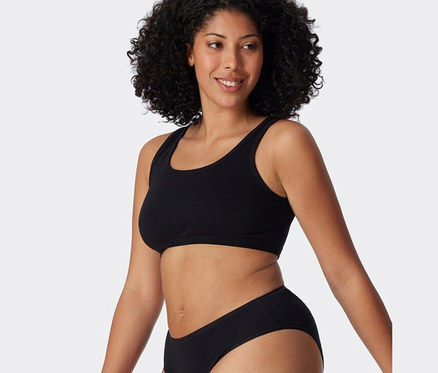 Frau trägt ein schwarzes SCHIESSER Bustier mit Bio-Baumwolle aus einem zweiteiligen Set.