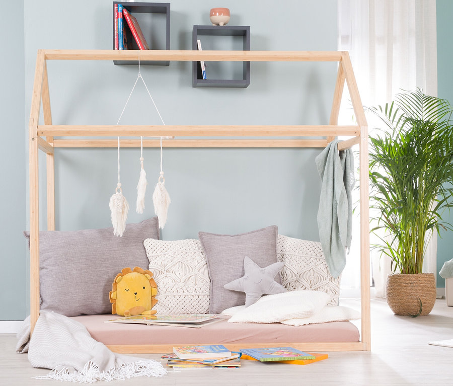 Ein roba Hausbett, ca. 70 x 140 cm, aus Bambus, umgeben von Kissen und Spielzeug.
