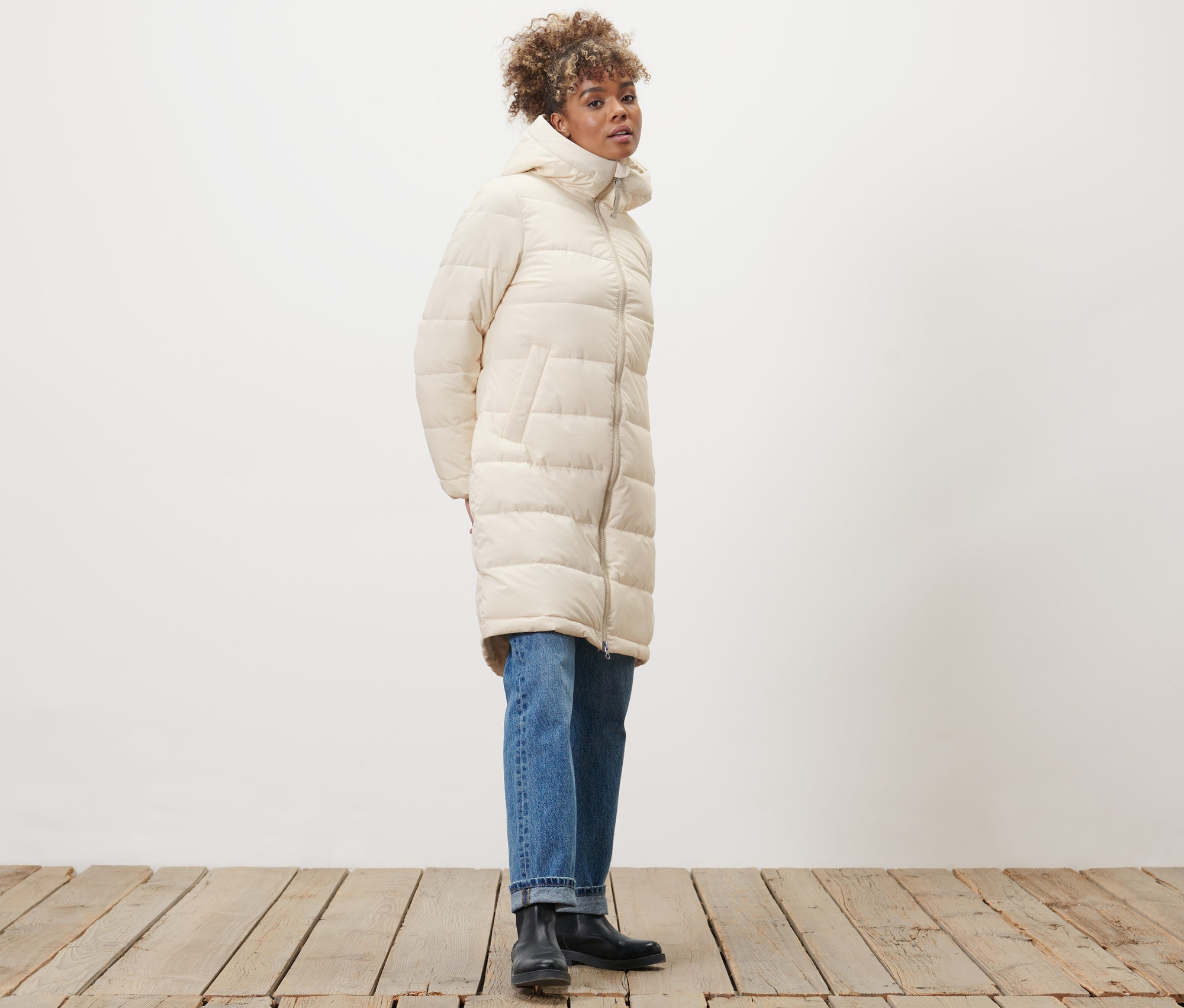 Frau posiert in beigem Steppmantel.