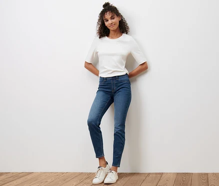 Frau posiert auf Holzboden in blauen Treggings »Fit Nelly« und weißem T-Shirt.