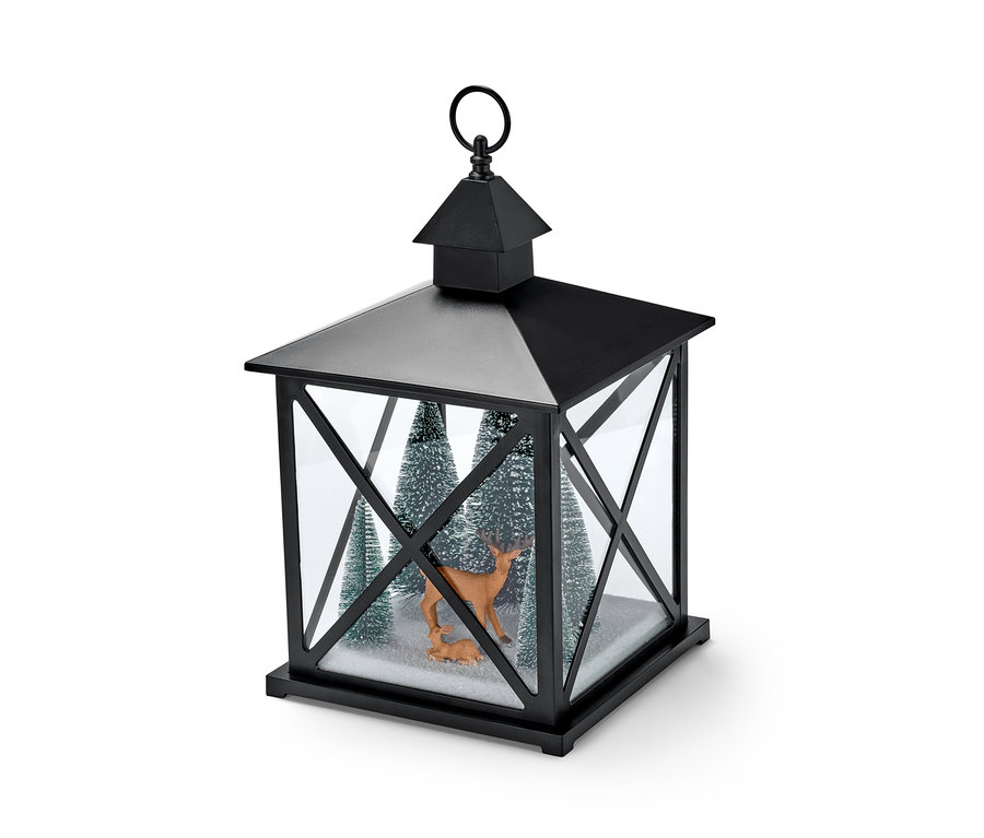 Eine schwarze LED-Dekolaterne mit zwei Rehfiguren und drei kleinen, beschneiten Bäumen im Inneren.