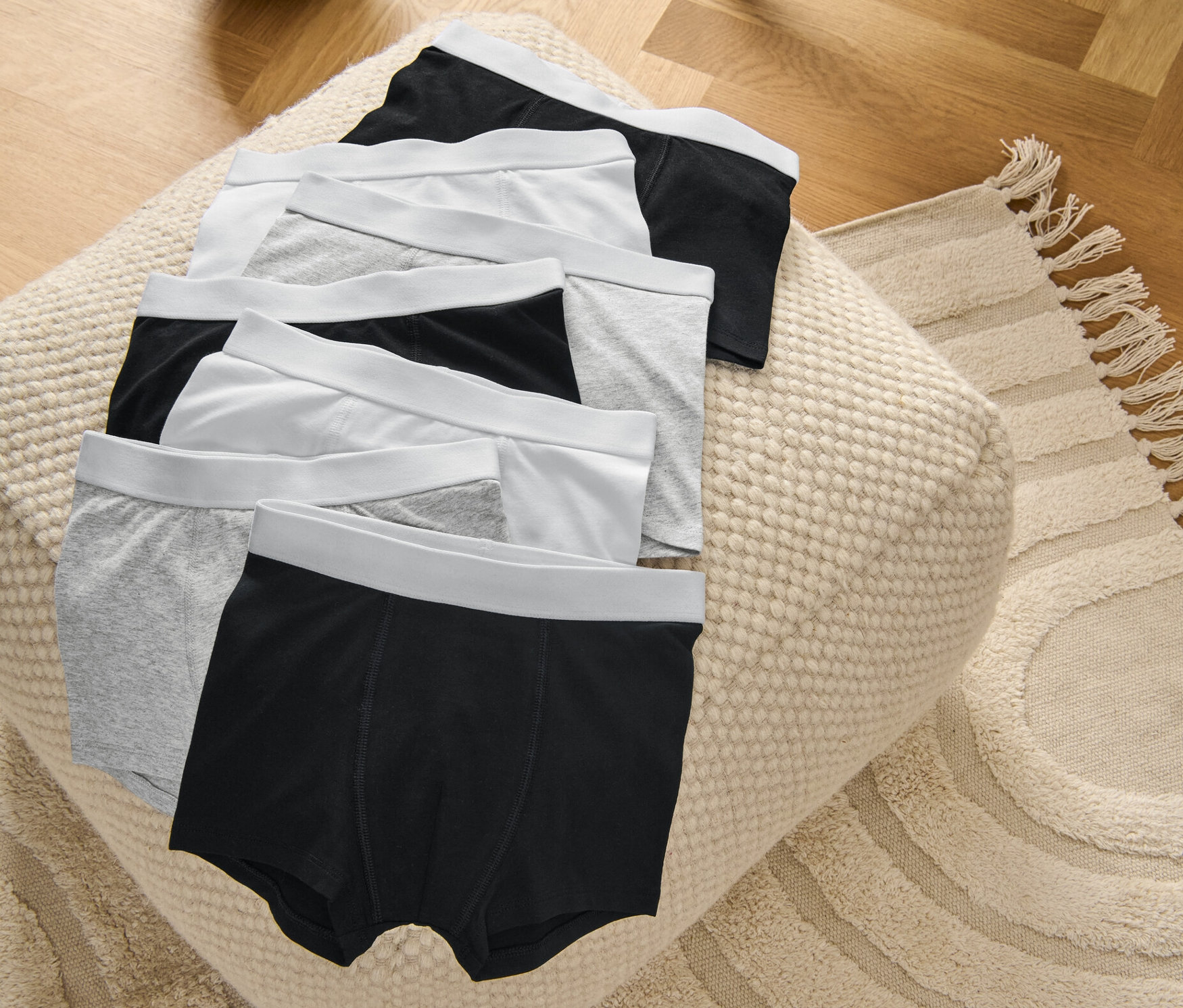 7 Kinder-Slipboxer, grau/weiß/schwarz, liegen auf einem Pouf.