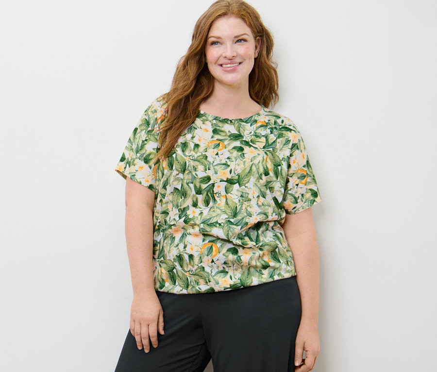 Eine Frau trägt ein bedrucktes Blusenshirt und eine Palazzohose.