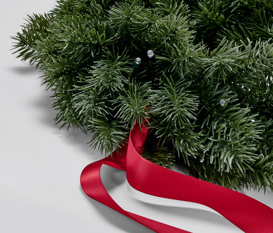 Nahaufnahme eines LED-Tannenkrans mit rotem Band.