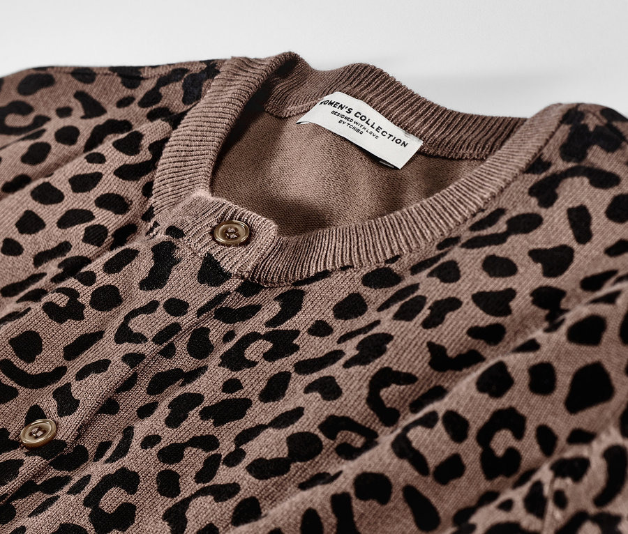 Detailansicht eines braunen, bedruckten Feinstrick-Cardigans mit schwarzem Tiermuster und Knöpfen.