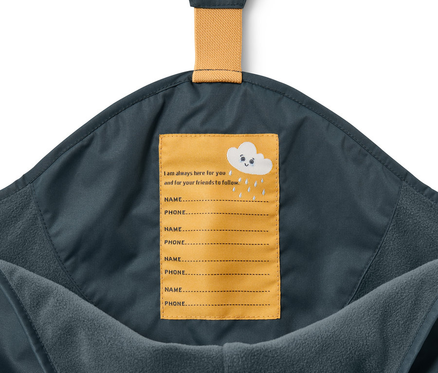 Detail einer Kinder-Thermo-Regenhose in Schieferblau mit gelbem Namensschild.