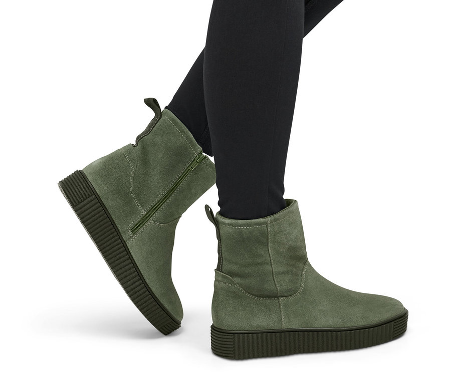 Beine in schwarzen Leggings und grünen Veloursleder-Boots.