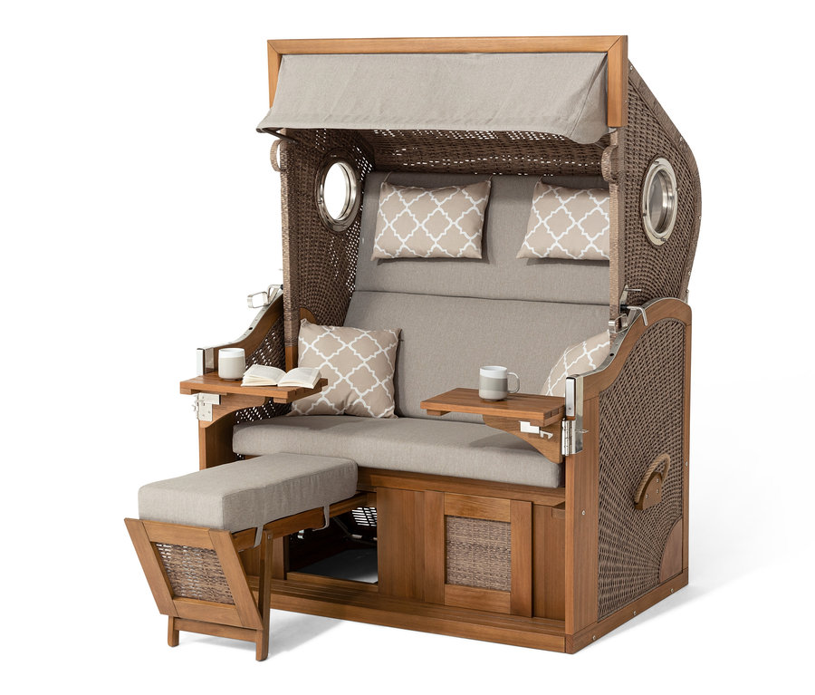 Nahaufnahme eines Premium-Strandkorbs XXL mit 2 Ausklapptischen, der eine braune Rattanstruktur und beige Kissen hat.