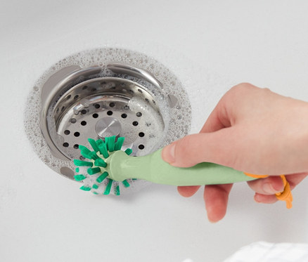 Frau reinigt Spüle mit Universalreinigungsbürste.