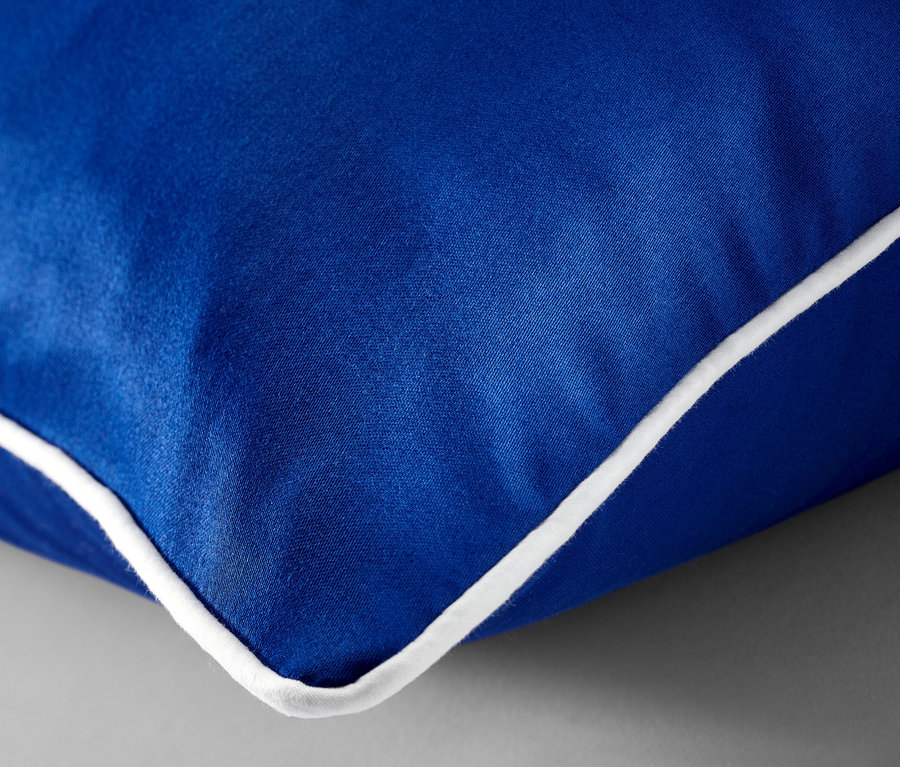 Detailaufnahme von blauer Satin-Bettwäsche in Normalgröße mit weißer Bordüre.