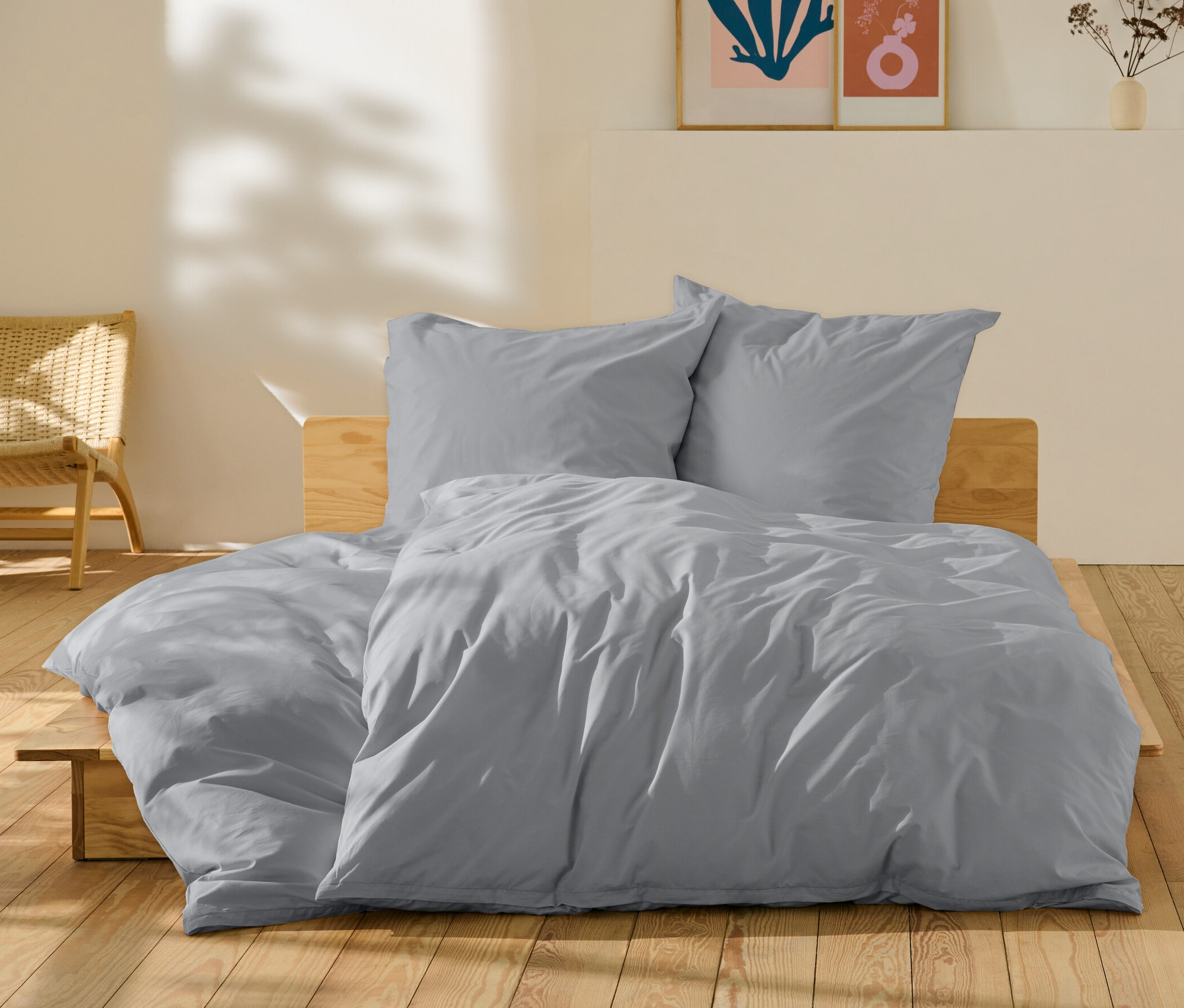 Graue Perkal-Bettwäsche in Normal- und Übergröße auf einem Bett.