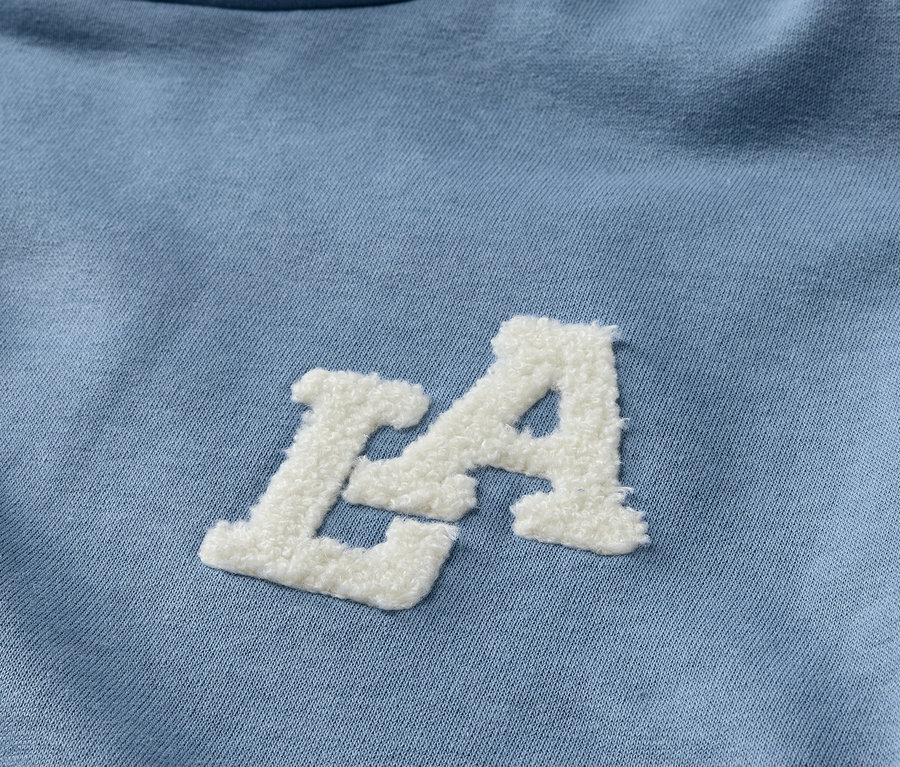 Detailansicht eines hellblauen Kinder-Sweat-Hoodies mit weißem LA-Schriftzug.