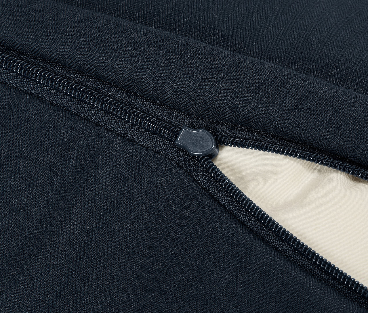Detailaufnahme eines blauen Textilprodukts mit geöffnetem Reißverschluss, der ein beiges Interieur enthüllt.