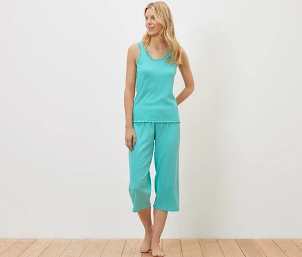 Blonde Frau steht und trägt ein geripptes Pyjama-Set.