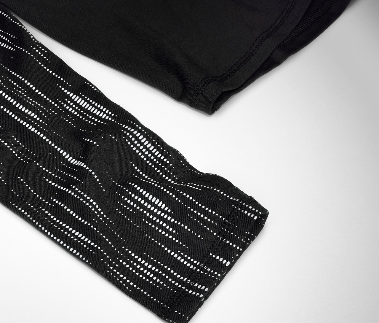 Detailaufnahme eines schwarzen Langarmshirts mit weißem Punktmuster auf dem Ärmel.