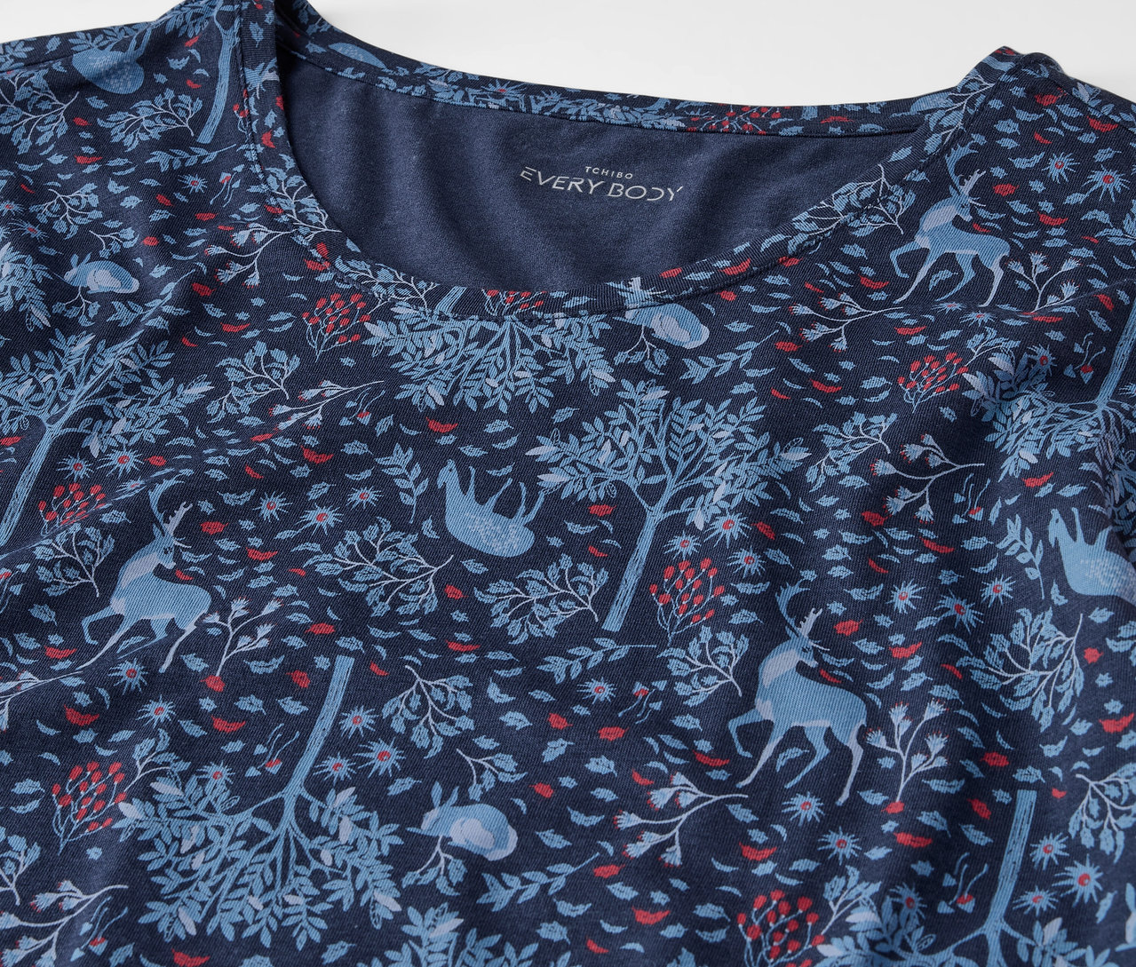 Detail eines marineblauen T-Shirts mit Baum- und Tiermuster.