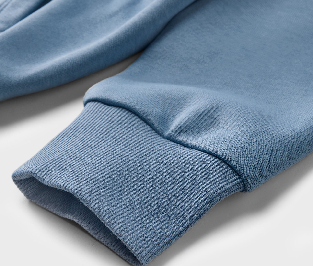 Detailansicht eines hellblauen Kinder-Sweat-Hoodies mit geripptem Bündchen am Ärmel.
