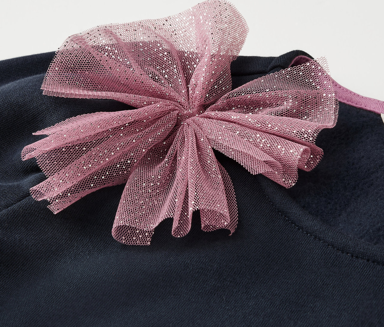 Dunkelblaue Kleidung mit rosa Schleife.