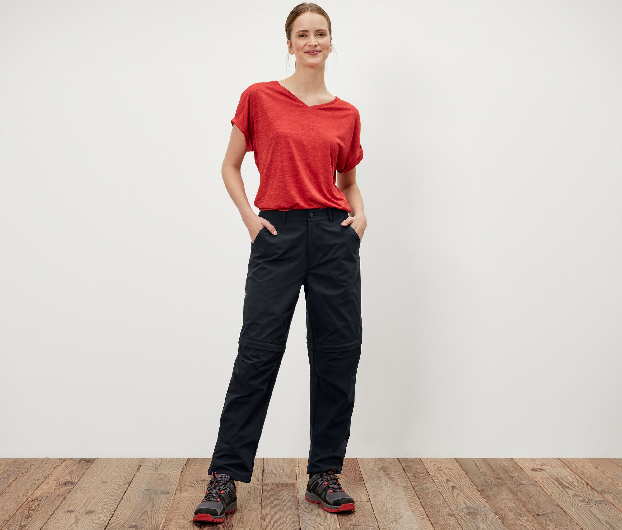 Frau steht mit Händen in den Taschen der schwarzen 2-in-1-Funktionshose.