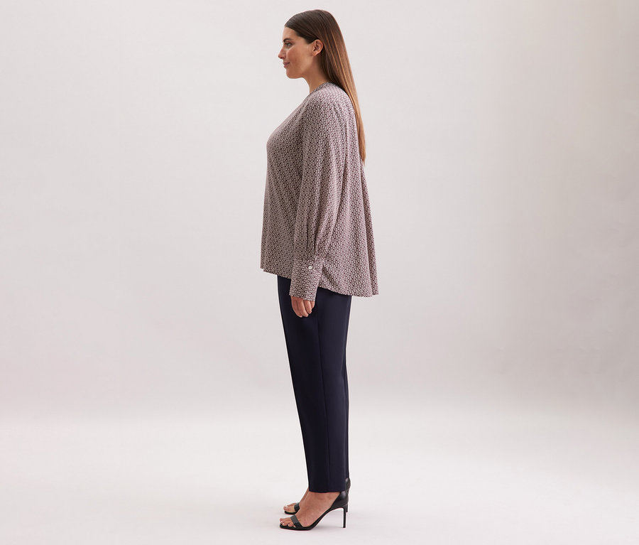 Frau trägt eine Seidensticker Tunika aus Viskose mit ecru-burgundy Alloverprint, kombiniert mit einer dunklen Hose und schwarzen High Heels.
