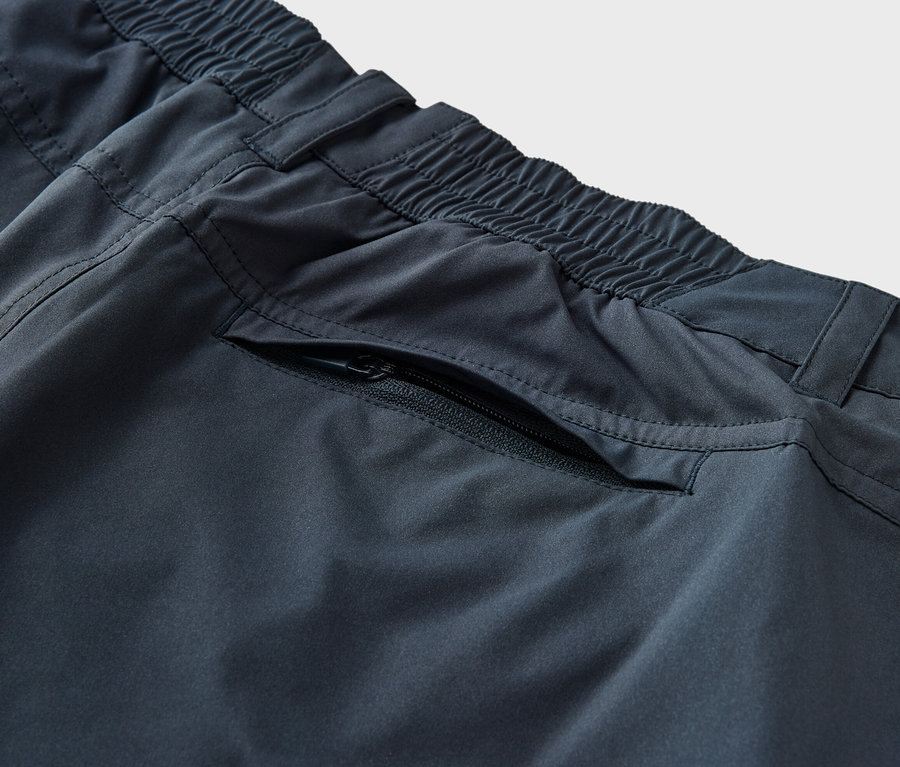 Detailaufnahme einer blauen 2-in-1-Funktionshose mit Gummibund und Reißverschlusstasche.