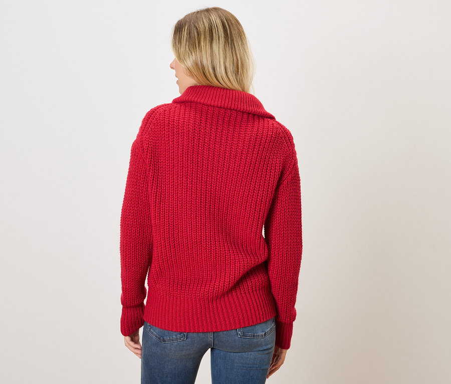 Frau von hinten in rotem Strickpullover und blauen Jeans.