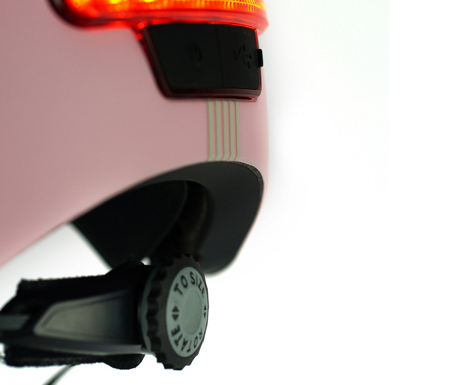 Detailansicht eines rosa Melon E-Series Fahrradhelms »Lotus« mit rotem Licht und Größenverstellrad.